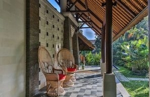 A covered outdoor seating area with wicker chairs and a checkered floor, surrounded by lush greenery. - The Manipura Luxury Estate & SPA 730sqm Living Area, 20m Iinfinity Pool (Ubud)