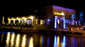 Ein Restaurant am Wasserufer mit Terrassensitzgelegenheiten und einer Steinfassade.