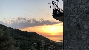 Un bâtiment en pierre doté d’un balcon donnant sur un coucher de soleil.