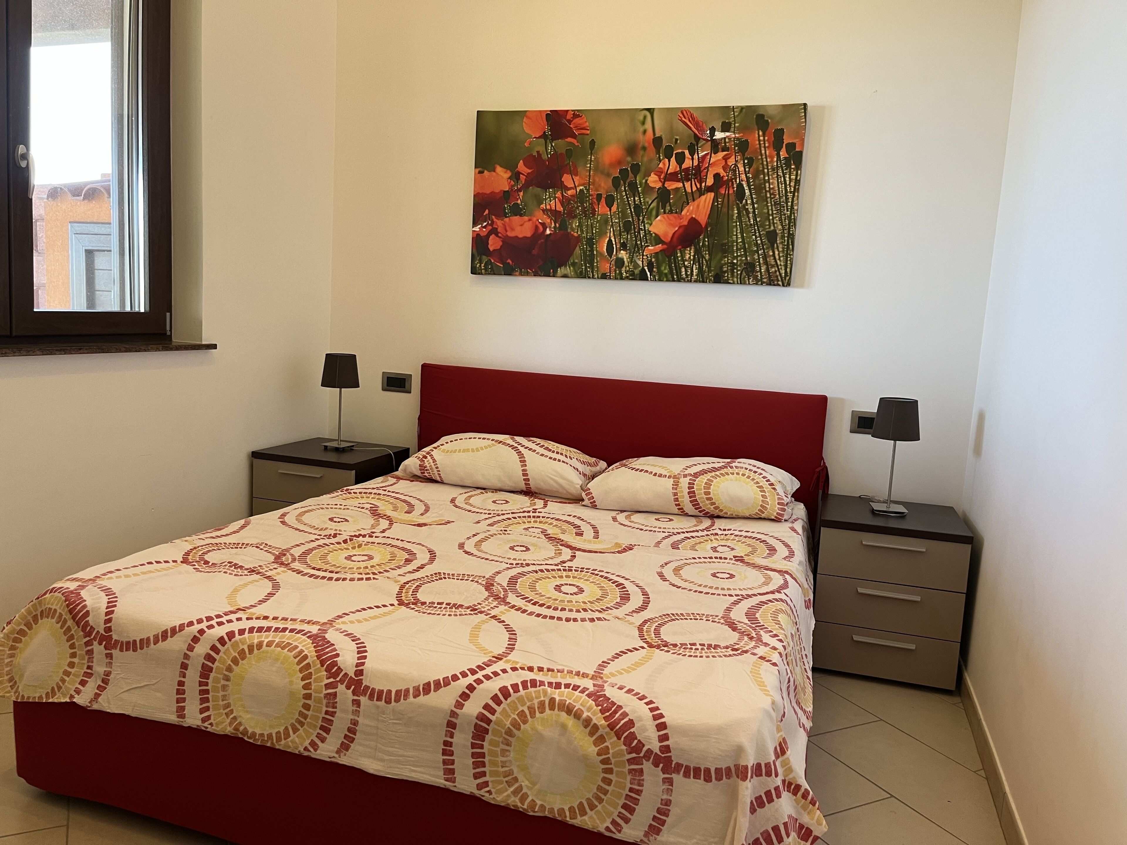 Una camera da letto con un letto, due comodini, una finestra e un quadro appeso al muro.