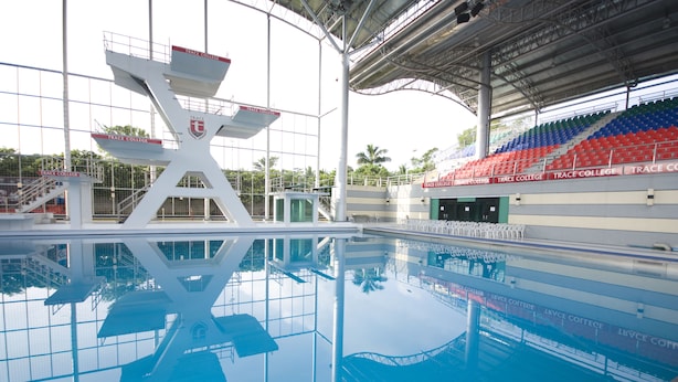 A swimming pool with diving platforms and bleachers. - Trace Suites by SMS Hospitality (Los Banos)
