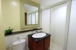 A modern bathroom with a toilet, sink, and mirror, featuring a small potted plant.