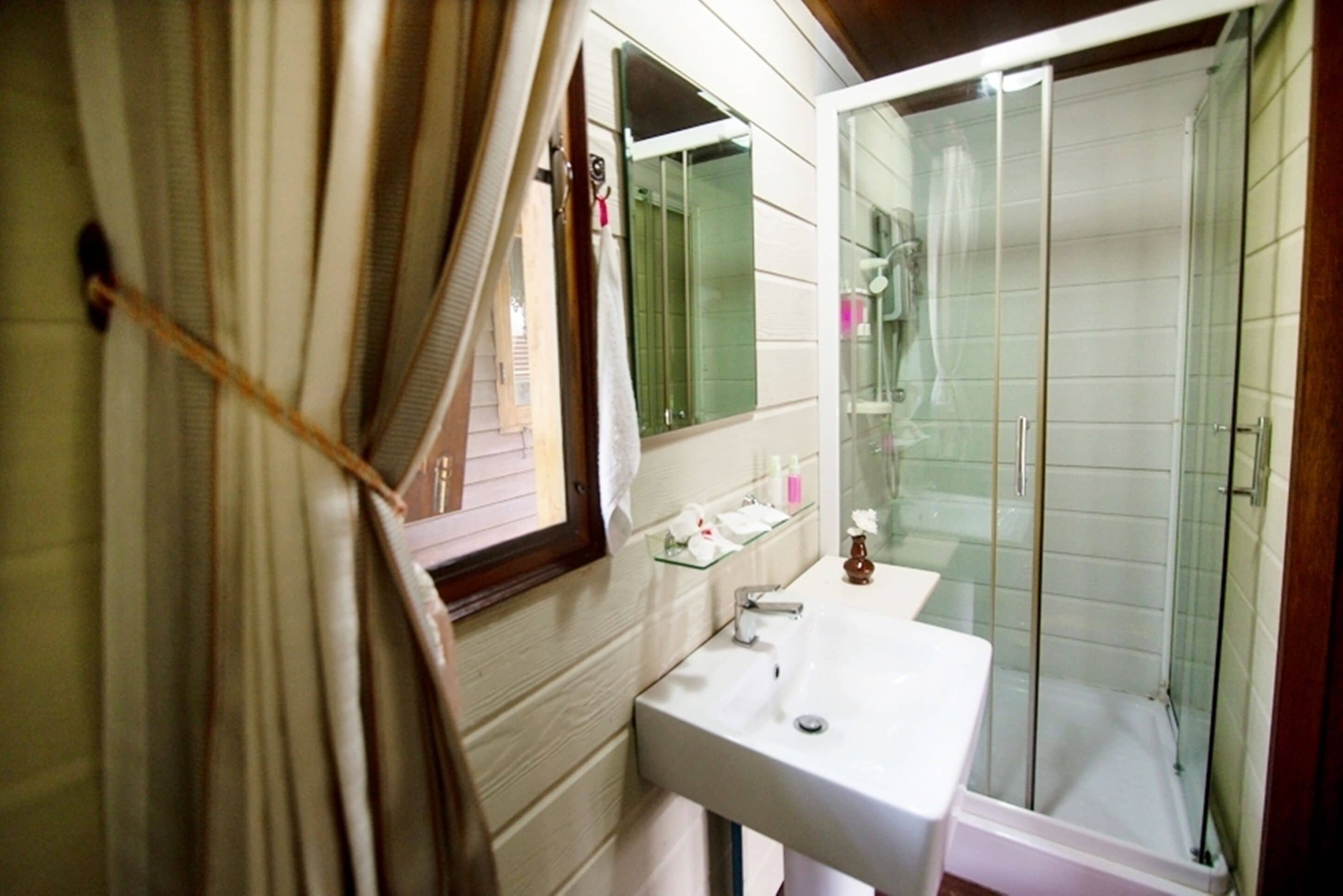 A bathroom with a white sink, glass shower enclosure, and a mirror above the sink.