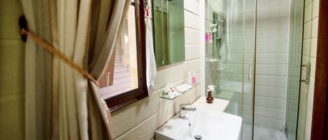 A bathroom with a white sink, glass shower enclosure, and a mirror above the sink.