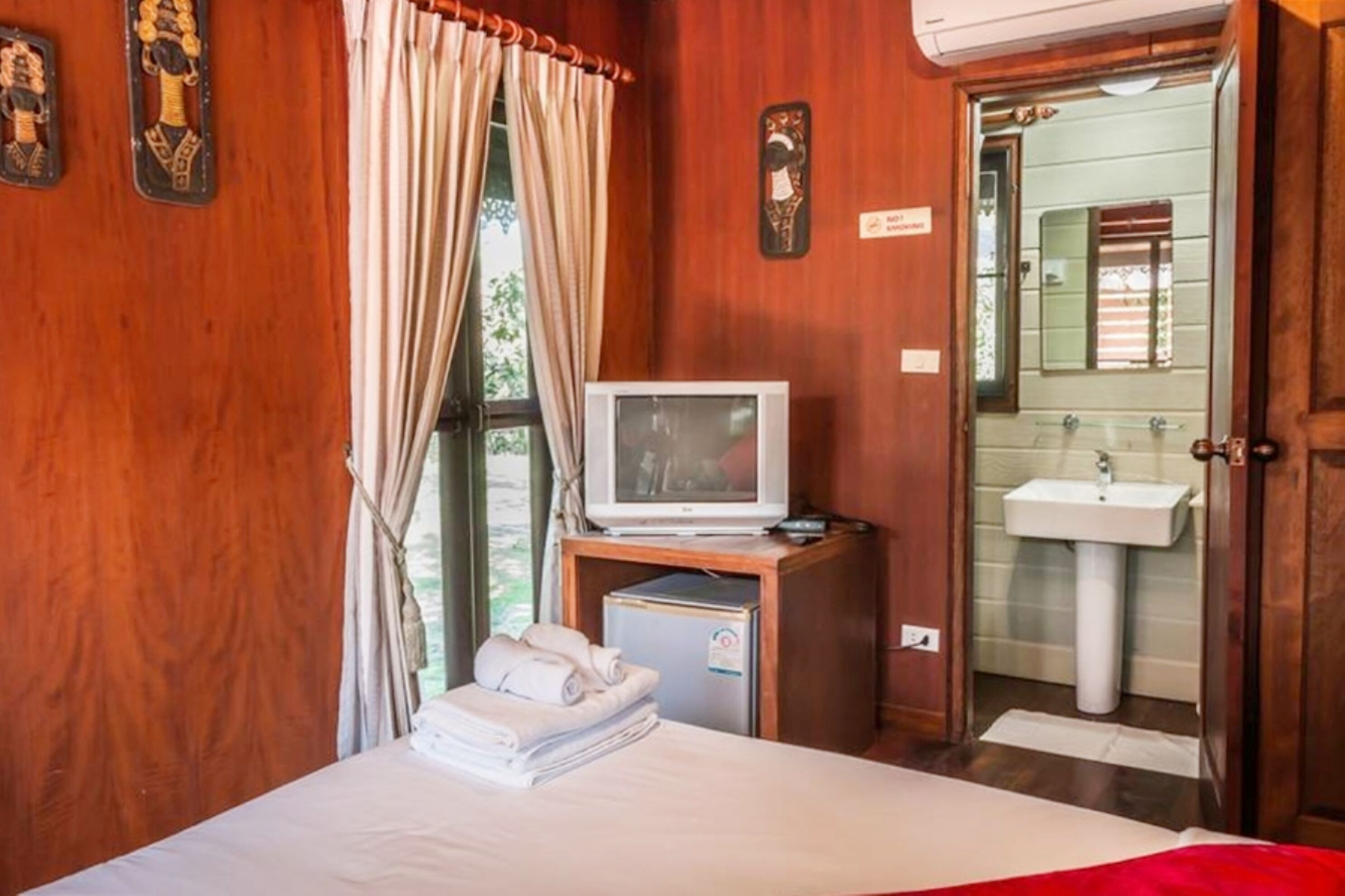 Une chambre d’hôtel équipée d’un lit, d’une télévision, d’un petit réfrigérateur et d’une salle de bain visible à travers une porte ouverte.