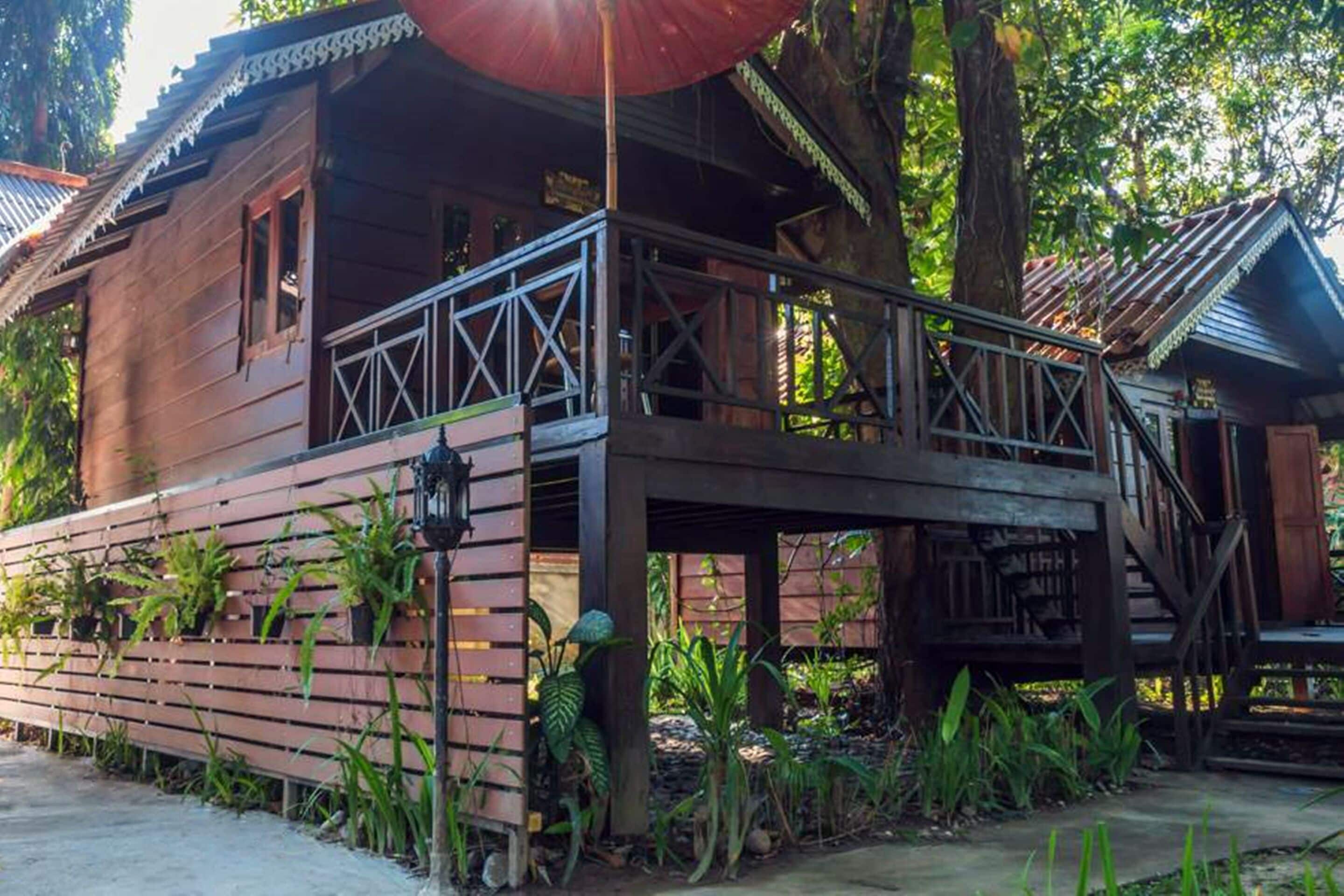 A wooden house with a balcony and a staircase leading to a covered area.
