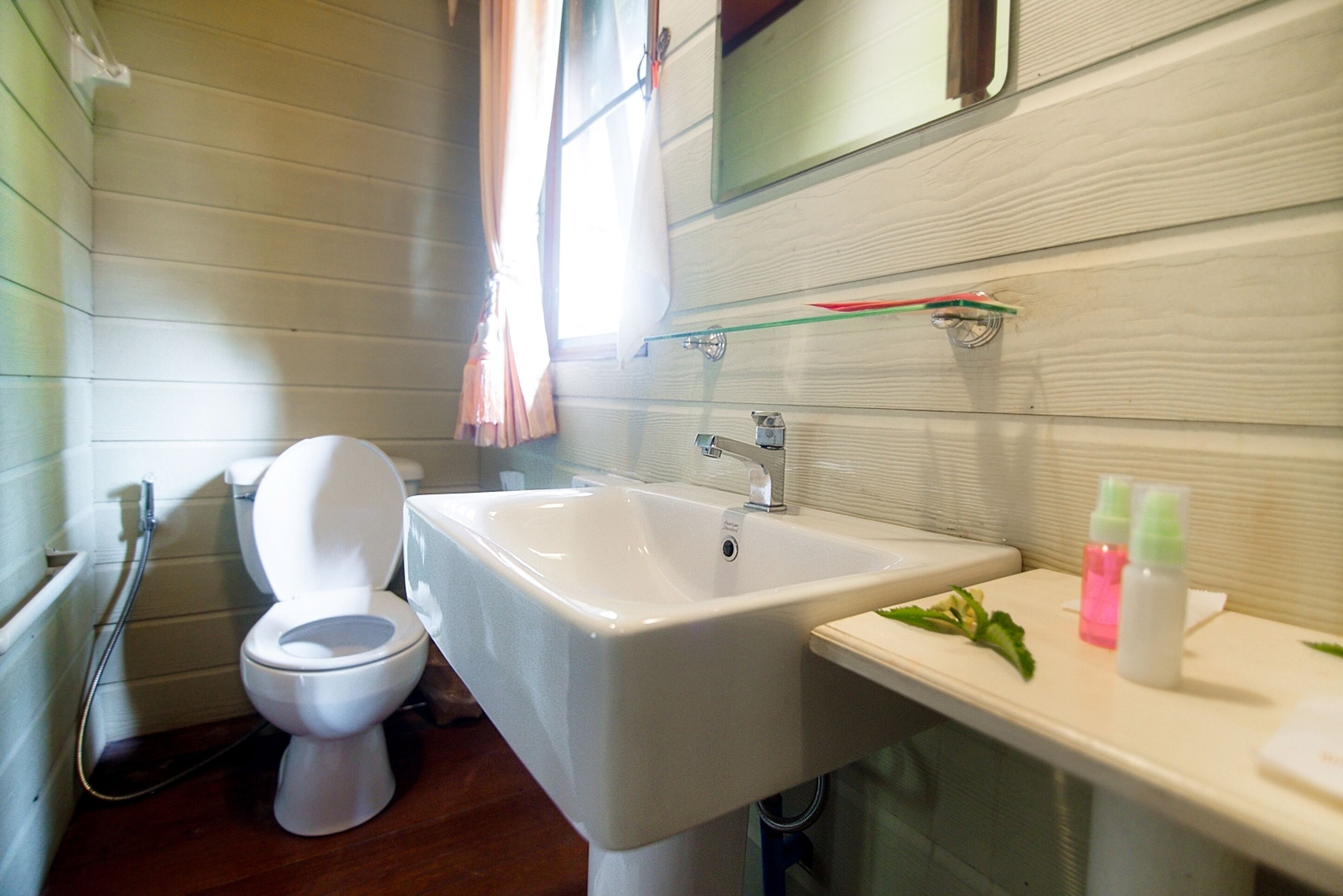 Une salle de bain avec des toilettes blanches, un lavabo blanc et un miroir au-dessus du lavabo.