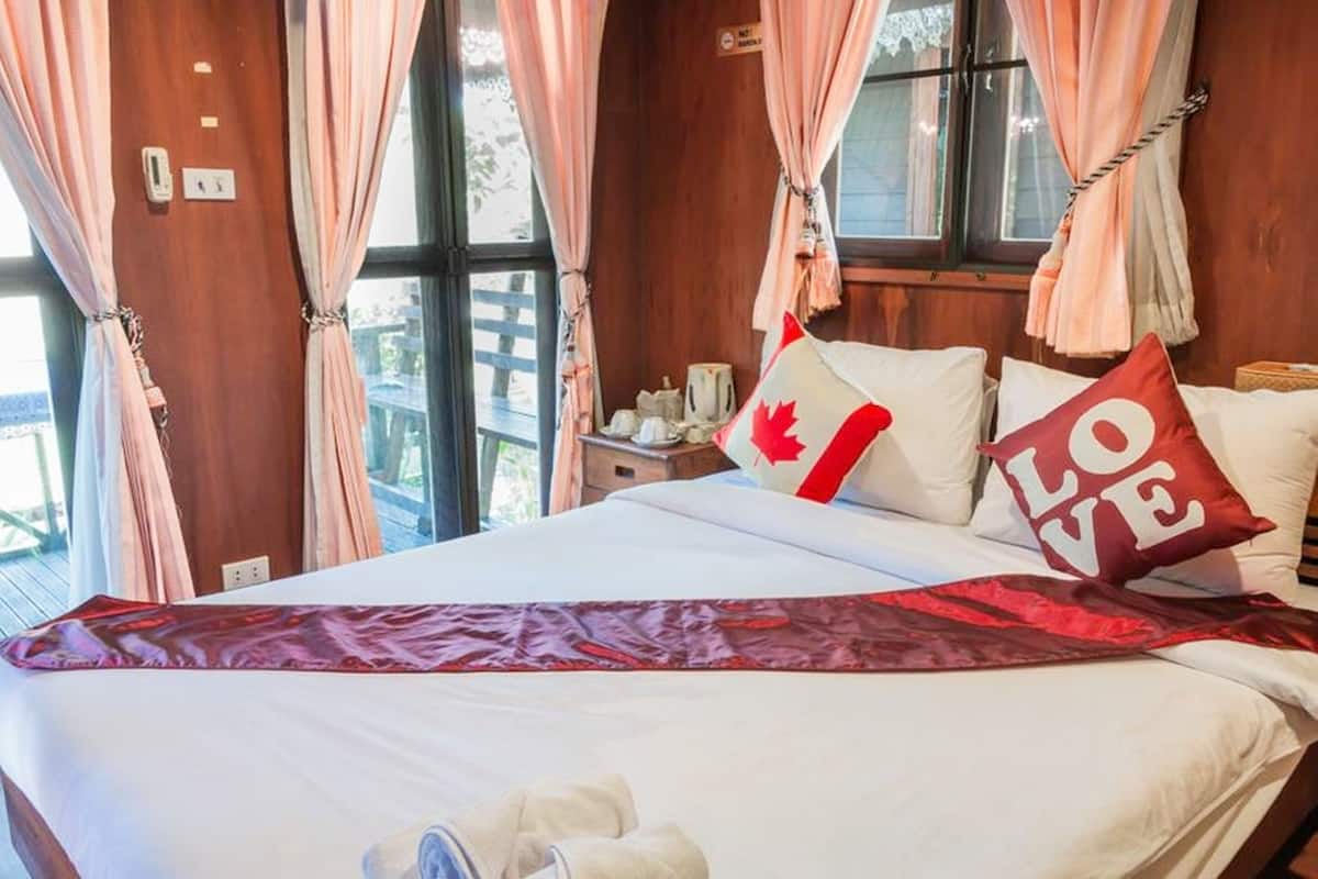 Ein Hotelzimmer mit einem Bett, einem Kopfkissen mit kanadischer Flagge, einem Kopfkissen mit dem Schriftzug "LOVE" und einer roten Decke.