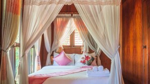 Een bed met een hemelbed, kussens en een opgerolde handdoek.