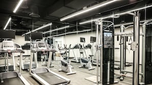 Une salle de sport équipée de tapis de course, de vélos elliptiques et de matériel de musculation.