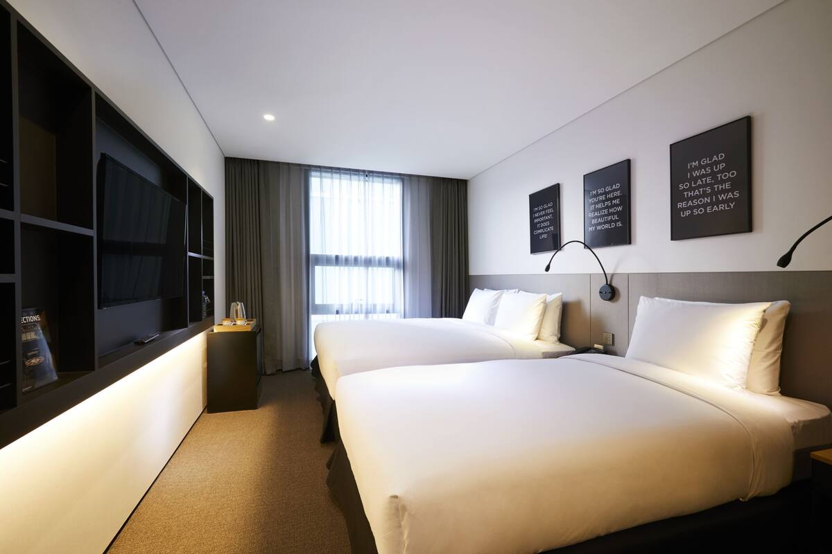 A hotel room with two beds, a TV, and a minibar.