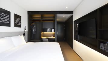 A modern hotel room with a large bed, a desk, a wardrobe, and a TV.