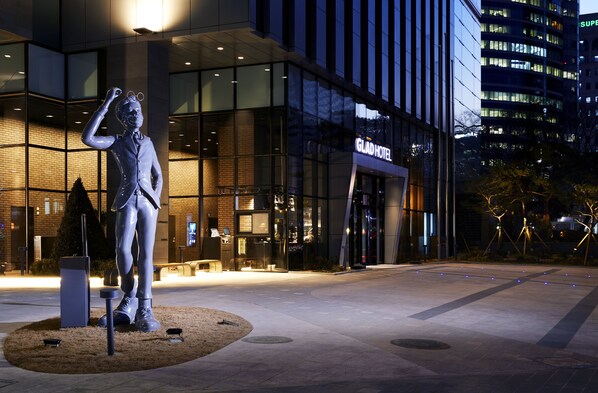 A modern hotel with a glass facade, a prominent statue in front, and a well-lit entrance. - GLAD Gangnam COEX Center (Seoul)