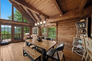 A wooden interior with a dining table, chairs, and a bench.