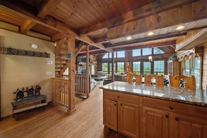 A wooden interior with a kitchen island, wooden bench, and a staircase.