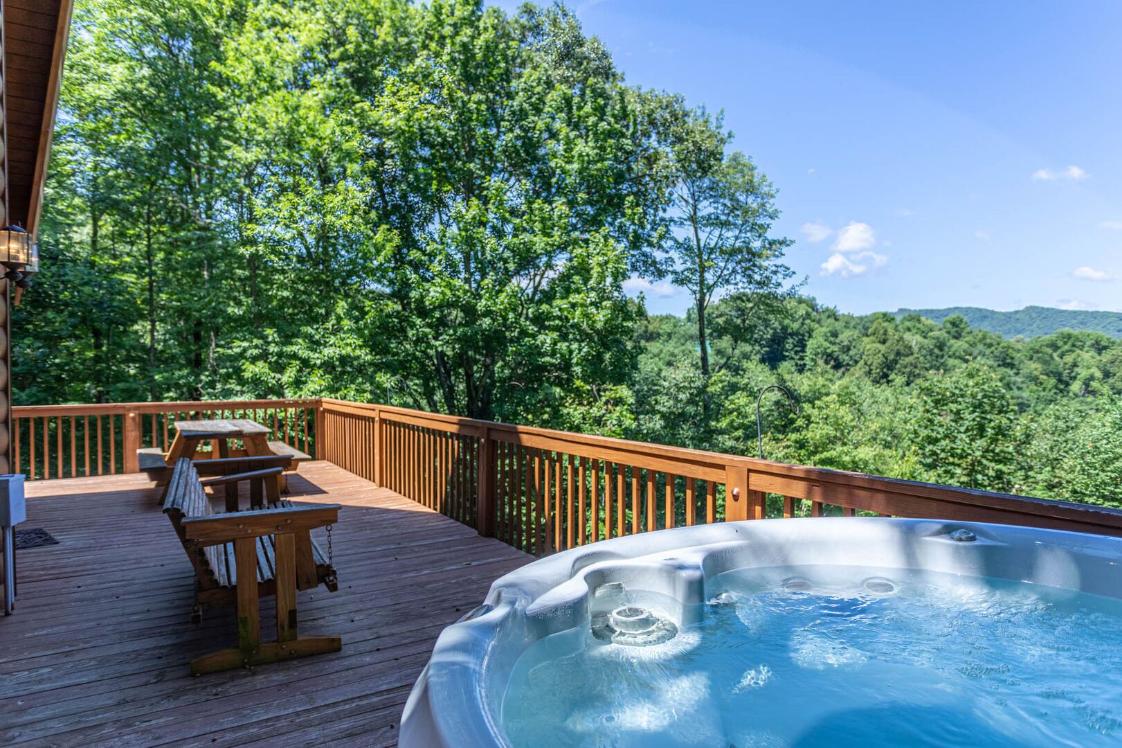 A wooden deck with outdoor seating and a hot tub.