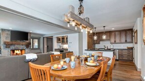 A modern kitchen with a stone fireplace, wooden cabinets, and a dining area with a wooden table and chairs.