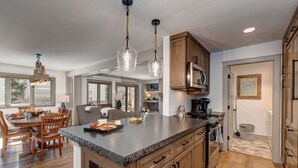A spacious kitchen with a large island, wooden cabinets, and a modern pendant light.