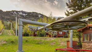 A ski lift structure, a wooden cabin, and a mountainous backdrop.
