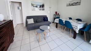 A modern living room with a sofa, dining table, chairs, and a hanging light fixture. - Terraced villa in front of the sporting casino (HOSSEGOR)
