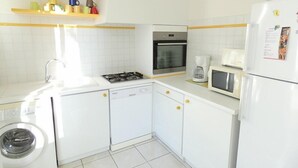 A compact kitchen with white cabinets, a washing machine, a stove, an oven, a microwave, and a refrigerator. - Terraced villa in front of the sporting casino (HOSSEGOR)