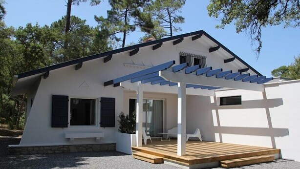 A modern house with a covered porch, a wooden deck, and a stone foundation. - Terraced villa in front of the sporting casino (HOSSEGOR)
