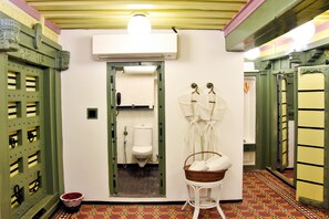 Casa de banho com sanita, lavatório e espelho. Há uma cesta com toalhas sobre uma pequena mesa.