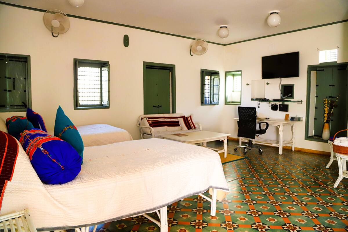 Ein Hotelzimmer mit Bett, Schreibtisch, Stuhl, Fernseher und einem Badezimmer mit Spiegel und Waschbecken.