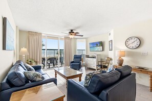 A modern living room with a sofa, coffee table, and a TV on a wall. - Great Oceanfront Condo - Recently Re-Furbished + Free Attraction Tickets! (North Myrtle Beach)