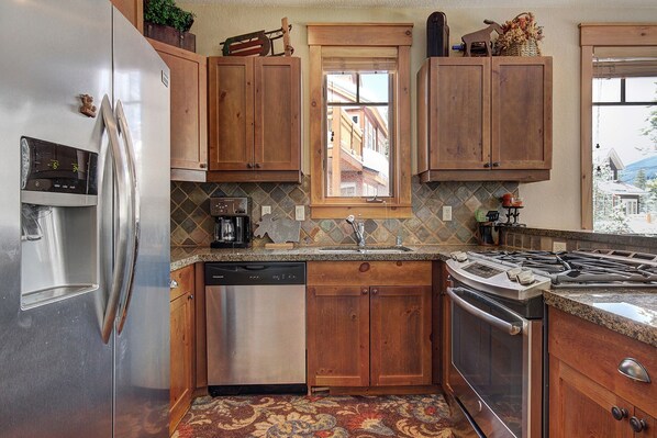 Una cocina con armarios de madera, un refrigerador de acero inoxidable, una cafetera y una estufa.