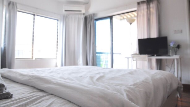 Ein Hotelzimmer mit einem großen Bett, einem Fernseher auf einem Schreibtisch und Blick ins Freie durch große Fenster.