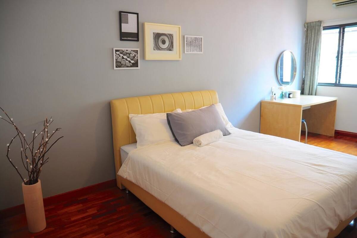 A neatly arranged bedroom with a bed, bedside table, and a mirror.