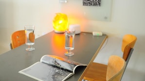 Ein Tisch mit einer Zeitschrift, zwei Gläsern Wasser, einer Salzlampen und einem kleinen, weißen Gerät.