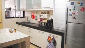 Eine Küche mit weißen Schränken, einer schwarzen Arbeitsplatte und einem Edelstahl-Kühlschrank.