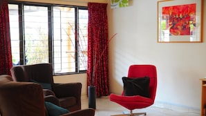 Ein modernes Wohnzimmer mit einem roten Sessel, braunen Sofas und einem großen Fenster mit roten Vorhängen.