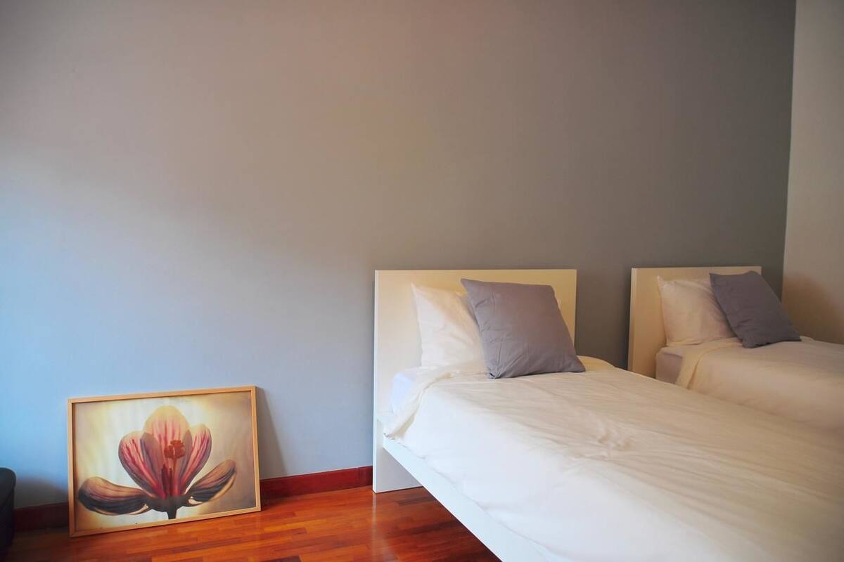 A room with two single beds, a framed picture of a flower, and a wooden floor.