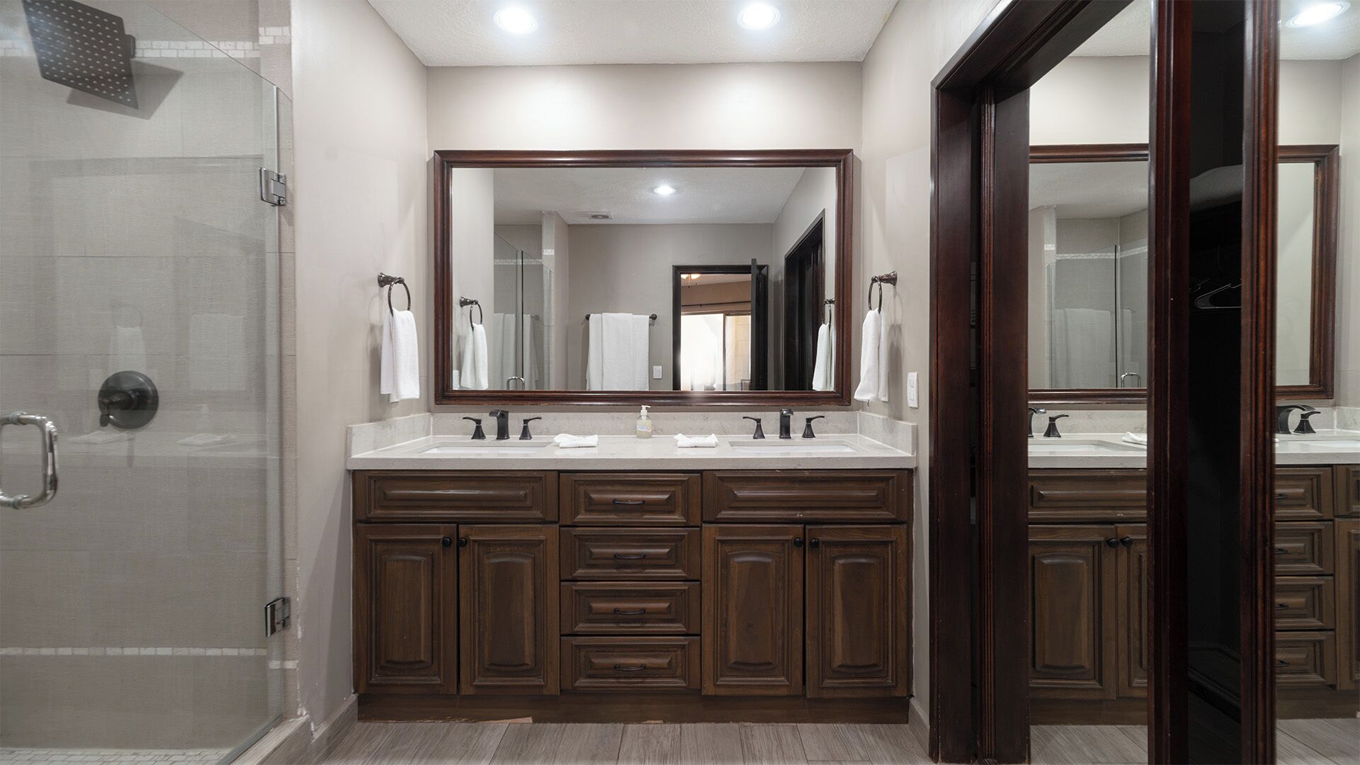 A modern bathroom with a double vanity, a large mirror, and a walk-in shower.