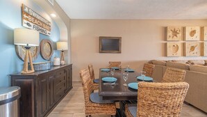 A dining area with a dark wooden table set for four, surrounded by wicker chairs.