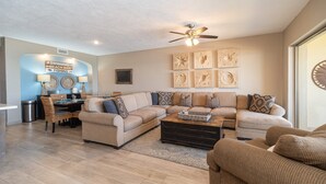 A living room with a sectional sofa, a coffee table, and a dining area with a table and chairs.