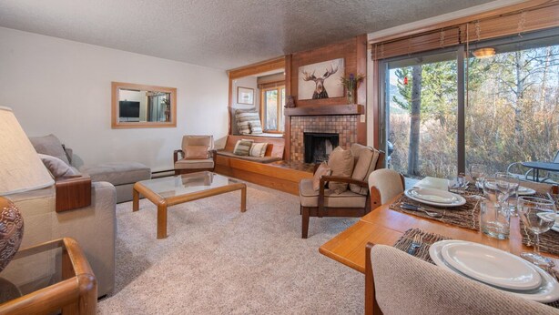 A cozy living room with a fireplace, comfortable seating, and a dining area set for a meal.
