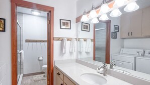 A modern bathroom with a large mirror, a sink, and a shower area.