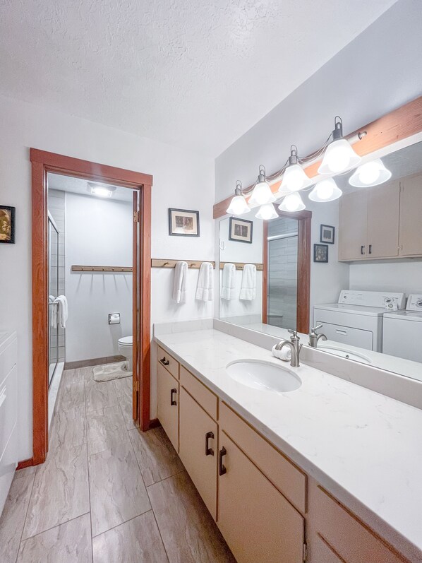 A modern bathroom with a large mirror, a sink, and a shower area. - JHRL - Aspens Bearberry 3412 - First floor Aspens condo with Teton views (Wilson)