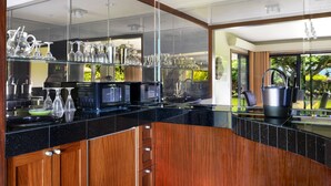 Une cuisine moderne avec un plan de travail noir, des armoires en bois et un pare-feu en verre.