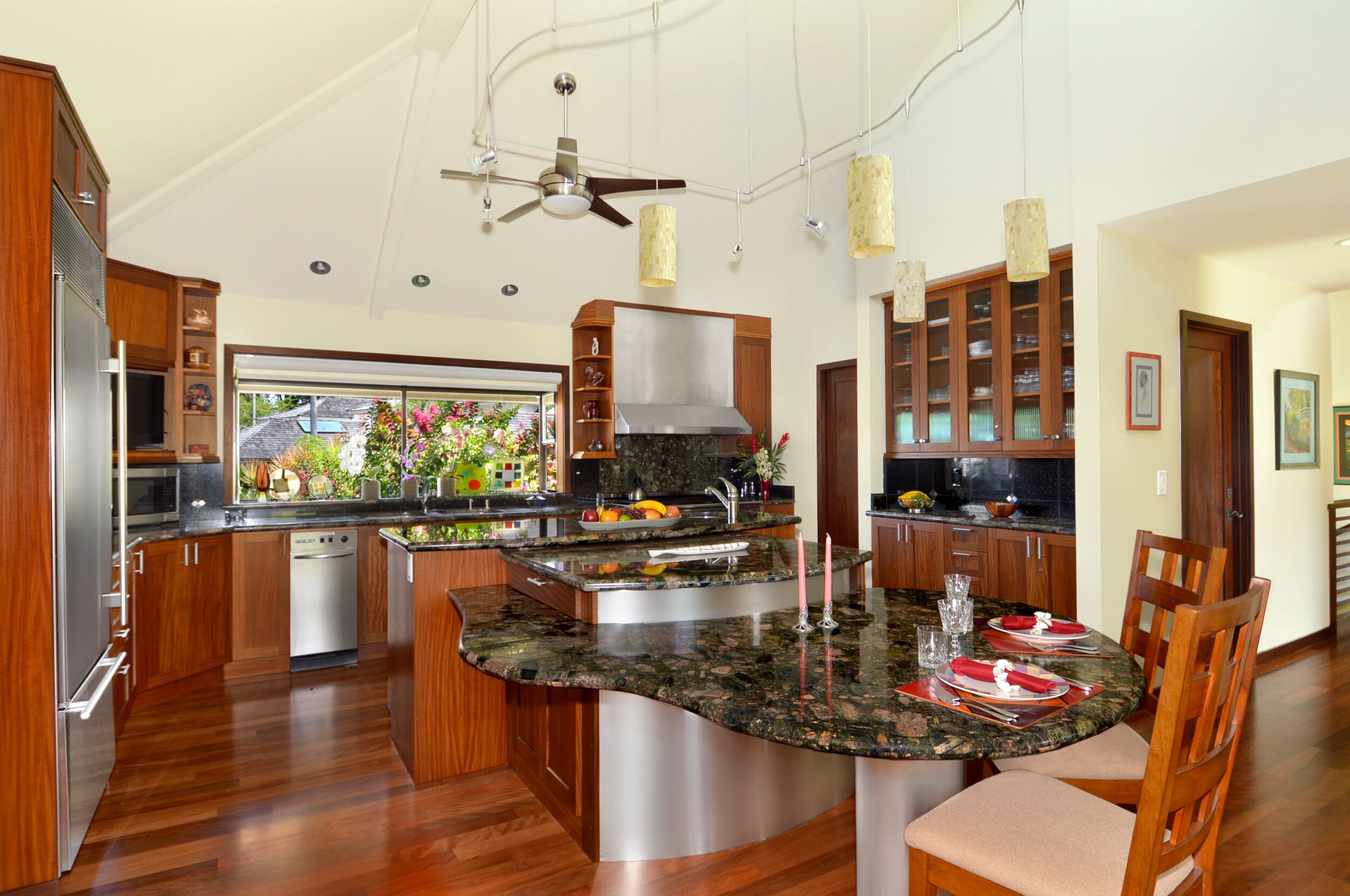 A modern kitchen with a central island, wooden cabinets, stainless steel appliances, and pendant lighting.