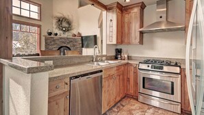 Una cocina moderna con encimeras de granito, electrodomésticos de acero inoxidable, armarios de madera y una chimenea de piedra.