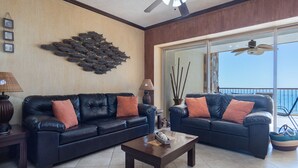 A living room with two black leather sofas, a wooden coffee table, and a decorative wall piece.