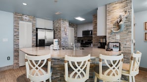 Cocina moderna con salpicadero de piedra, armarios blancos y una isla central con taburetes de bar.