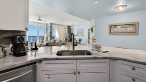Una cocina moderna con una isla grande, electrodomésticos de acero inoxidable y vistas al área de estar.