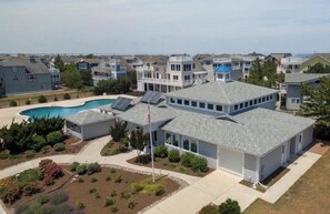 A residential building with a swimming pool, a flag, and a well-maintained lawn.