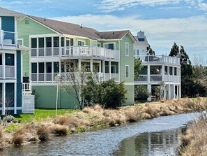 A two-story building with a balcony, a small porch, and a river in front.